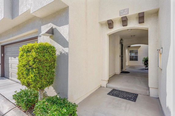 Entrance view of a house with stucco exterior and a garage door.