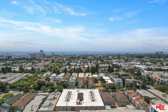 Panoramic view of a cityscape with residential and commercial buildings, and ocean in the distance.