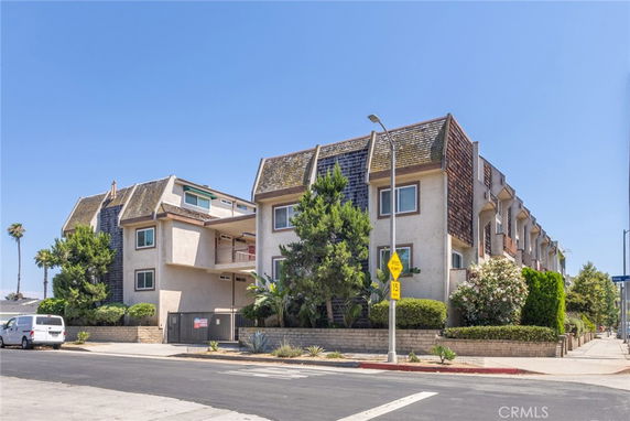 Front view of a multi-story residential building with wooden shingle siding and balconies.