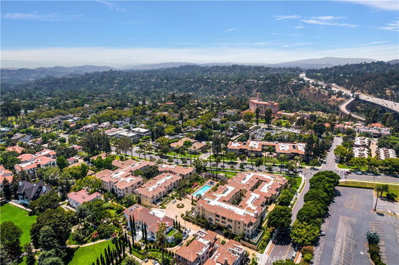 Panoramic view of a residential area with multiple buildings and greenery, seen from above.