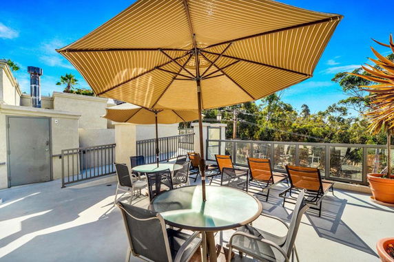 Rooftop view with seating area, umbrellas, and surrounding greenery.