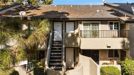Front view of a two-story residential building with exterior stairs and balconies.