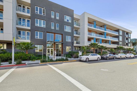 Front view of a modern multi-story apartment building with balconies.