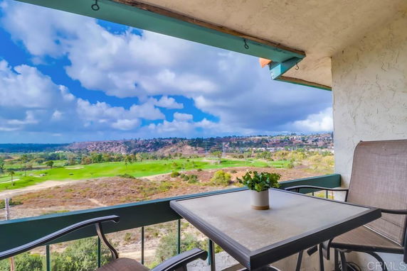 Balcony view overlooking a scenic landscape with hills and fields.