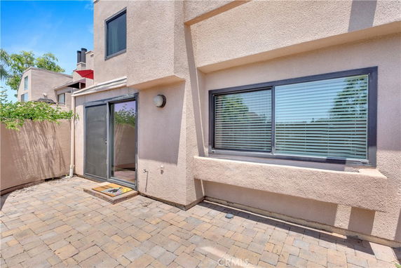Exterior view of a modern house with sliding glass door and large window.