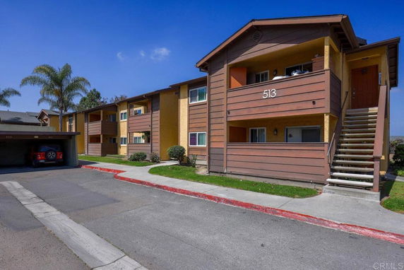Front view of a two-story apartment building with balconies and exterior stairs.