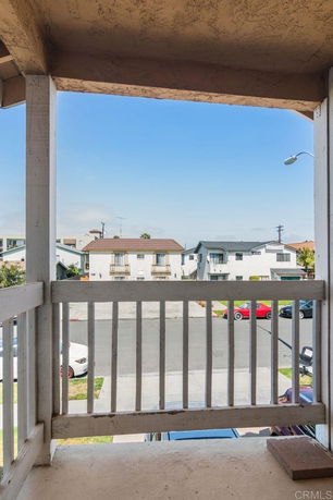 View from a balcony showing nearby residential buildings and street.