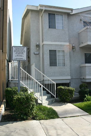 Front view of a multi-story building with stairs and a railing.