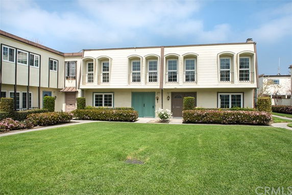 Front view of a two-story townhouse with white exterior and multiple windows.