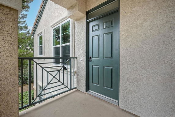 Entrance door on a balcony with adjacent windows and wrought iron railing.
