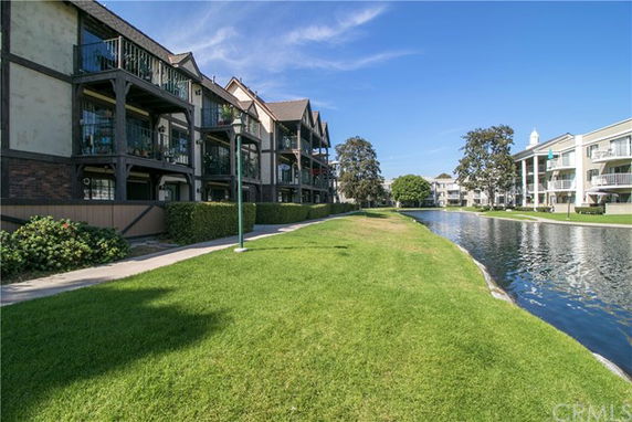 Front view of a multi-story residential building with balconies next to a water canal.
