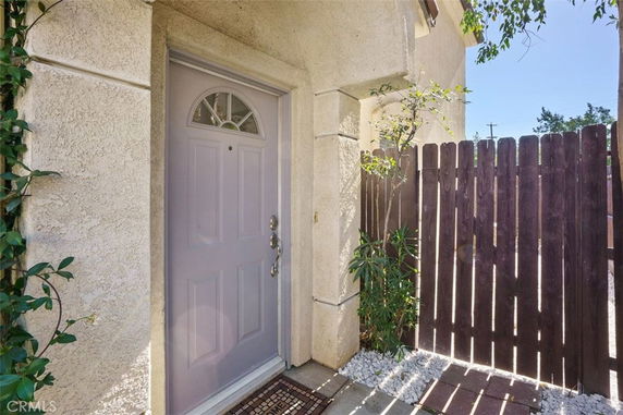 Entryway of a house with a lavender door and adjacent wooden fence.