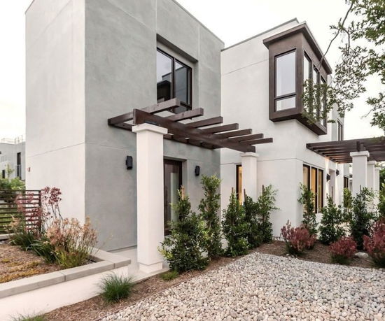 Front view of a modern two-story house with a pergola and large windows.