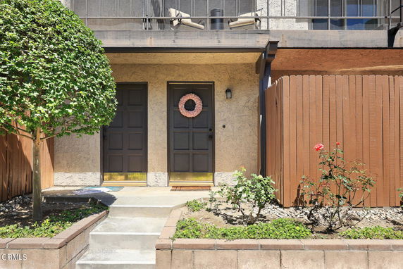Front view of a house entrance with two doors and a small garden area.