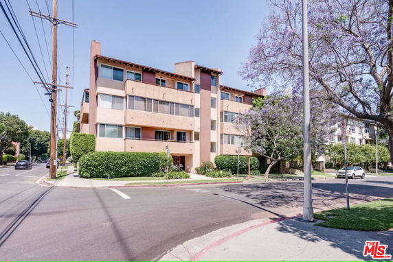 Front view of a multi-story apartment building on a street corner.