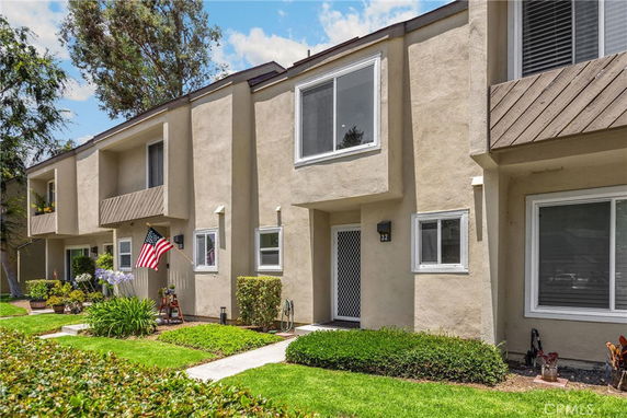 Front view of a two-story townhouse with beige exterior and large windows.