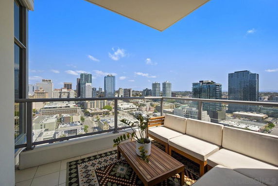 Panoramic view of city skyline from a high-rise balcony with seating.