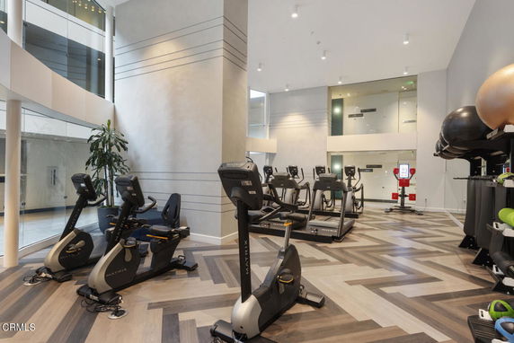 Modern indoor gym area with exercise equipment and glass walls.