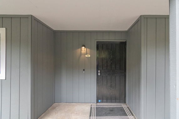 Front view of a house entrance with a dark door and gray paneling.