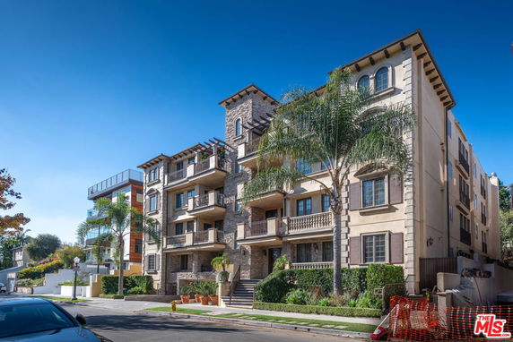 Front view of a multi-story residential building with balconies and stone facade.