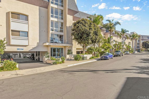Front view of a multi-story condominium building with large windows and covered parking area.