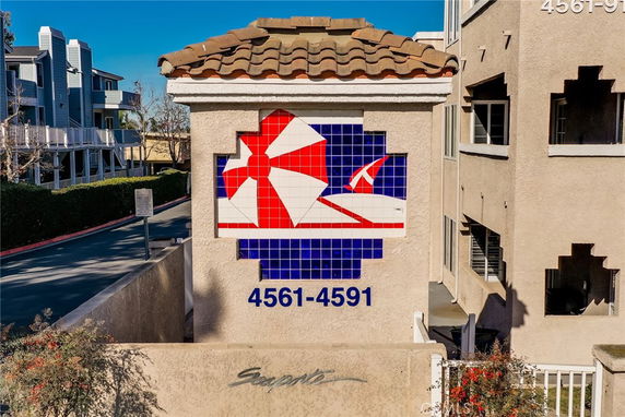 Front view of a building section with a decorative tile mural and building numbers.