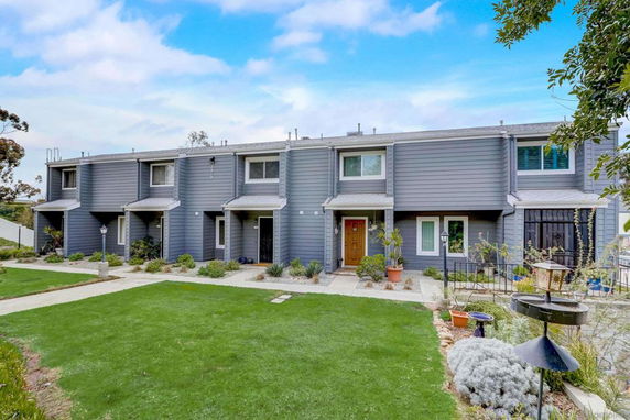 Front view of a row of two-story townhouses with gray siding and small front yards.