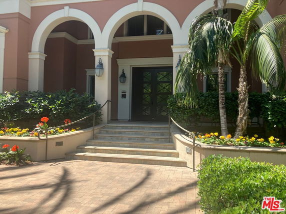 Front view of a building with arched entrance and landscaped surroundings.