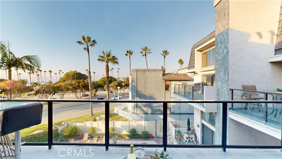 Elevated view from a balcony overlooking nearby buildings and palm trees.