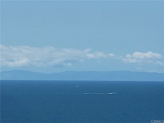 Wide angle view of the ocean with a boat and distant islands on the horizon.