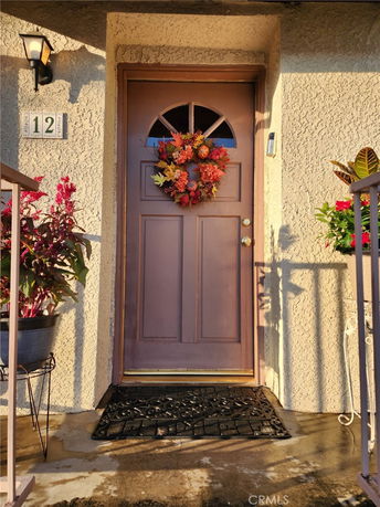 Front view of a house entrance with a door decorated with a wreath.