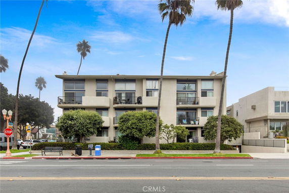 Front view of a multi-story residential building with balconies and large windows.