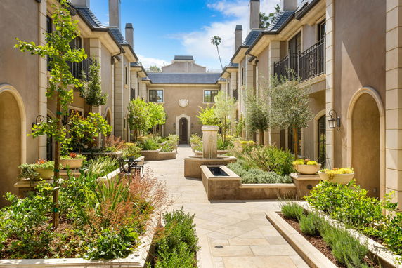Front view of a two-story building with a courtyard and lush landscaping.