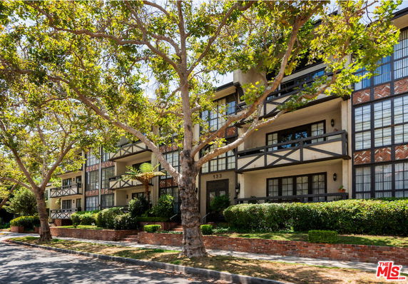 Front view of a multi-story residential building with balconies and decorative wooden beams.