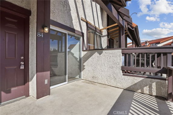 Partial view of building exterior with balcony and brown sliding glass door.