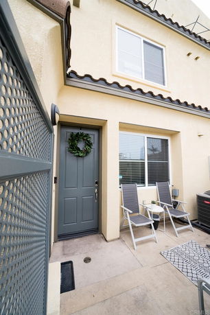 Front view of a two-story house entrance with a blue door and outdoor seating area.