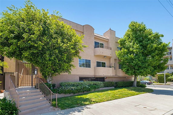 Front view of a multi-story residential building with a staircase and trees.