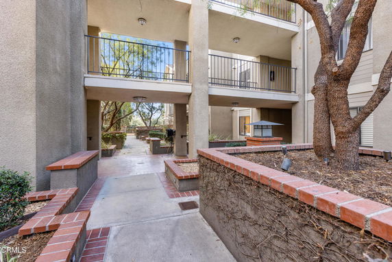Front view of a multi-story building with balconies and a pathway.