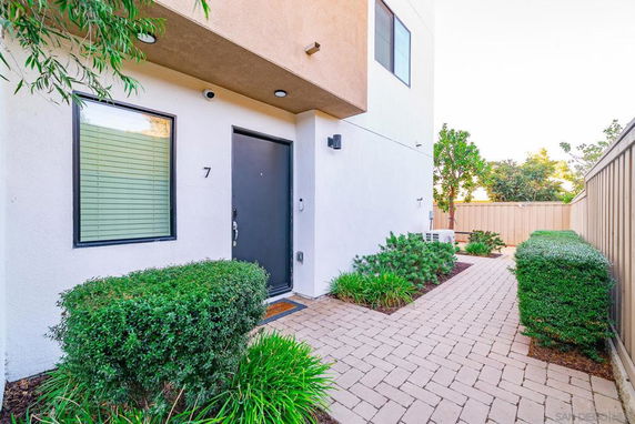 Front view of a modern two-story house with a black door and pathway.