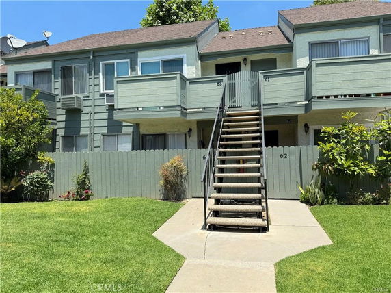 Front view of a two-story residential building with external staircase leading to upper units.