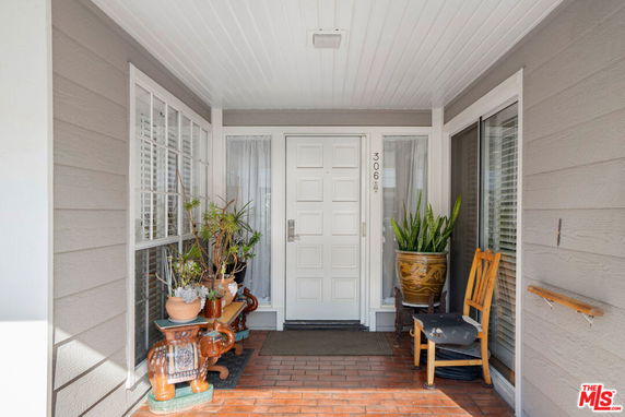 Front entrance view of a house with a white door and potted plants.