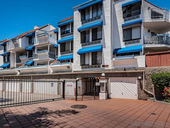 Front view of a multi-story building with balconies and blue awnings.