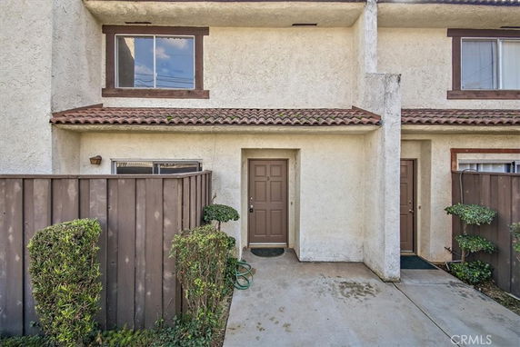 Front view of a two-story townhouse with a tiled roof and a small fenced entrance area.