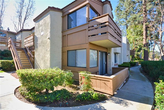 Front view of a two-story residential building with balconies and an outdoor staircase.