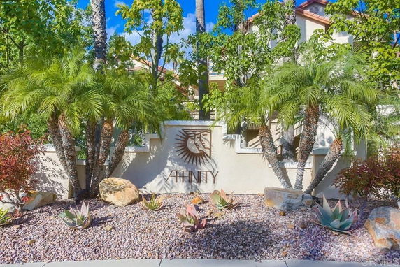 Front view of a building with palm trees and a decorative wall.