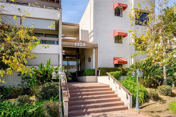 Front view of a multi-story building with entrance steps and red awnings.
