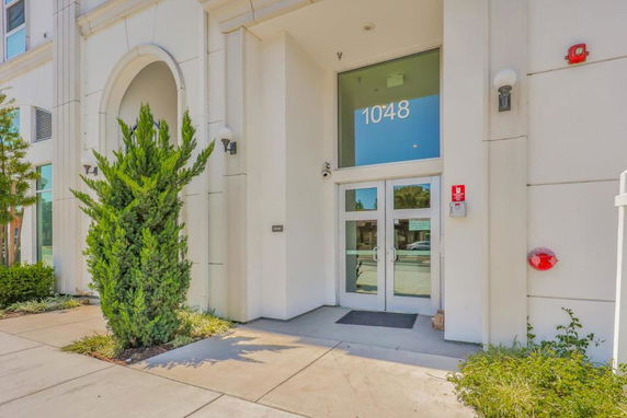Front view of a building entrance with glass double doors and the number 1048 above.