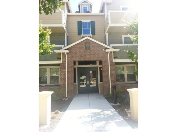 Front view of a multi-story residential building with a brick facade and balcony.