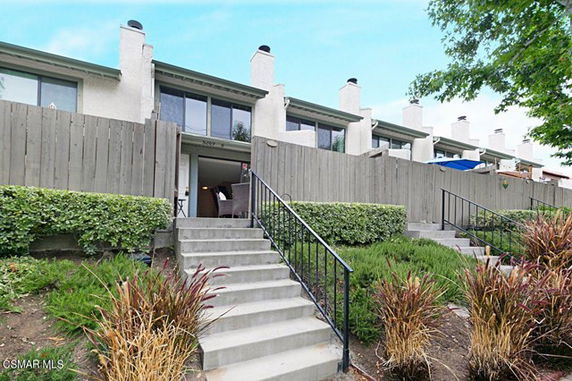 Front view of a multi-story townhouse complex with chimneys and stairs leading to entrances.