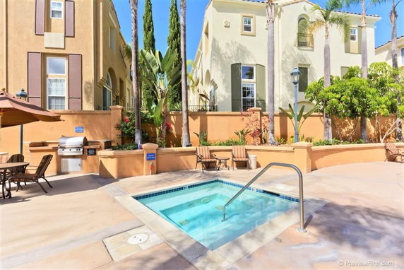 Outdoor area with a small swimming pool, surrounded by chairs and a barbecue setup in front of a two-story building.